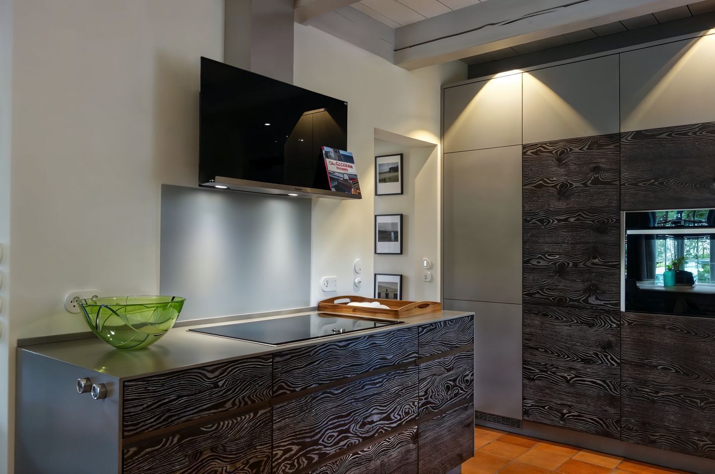 Una cocina moderna con estufa integrada, un cuenco de vidrio verde y una tabla de cortar de madera.