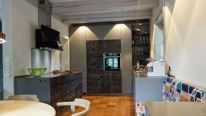 A compact kitchen with a built-in oven, a microwave, and a coffee machine. There is a dining area with a table and chairs. - Reethus main house on the ground floor/ first floor - Reethus in Borgsum: 121 m², sauna, fireplace & garden, (Borgsum)