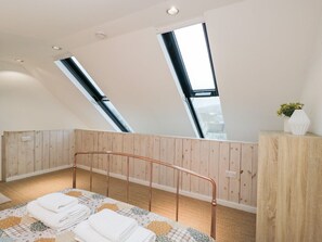 A bedroom with a sloped ceiling, skylights, a metal bed frame, a wooden cabinet, and a small plant. - 3 The Stoneyard, Bath (Bath)