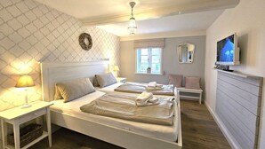 A bedroom with two beds, a TV, a window, and a ceiling fan. - WattGut - WattGut vacation home in Oevenum: sauna, wood-burning stove & garden for 6 guests (Oevenum)