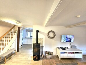 Ein modernes Wohnzimmer mit Kamin, Fernseher, einem weißen Schrank und einer Treppe, die in einen anderen Raum führt.