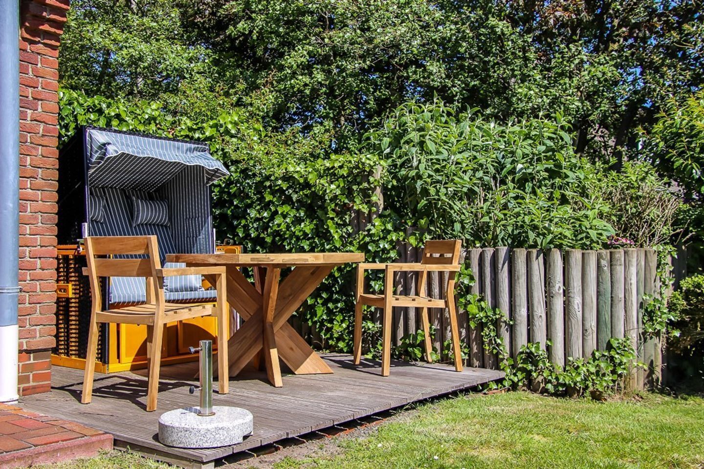 A patio with a wooden table and chairs, a covered seating area, and a brick wall.