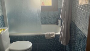 Un baño con inodoro, ducha, bañera y un taburete pequeño.