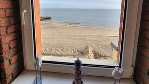 Una ventana con vista a una playa, una lámpara y una escultura de pájaro.