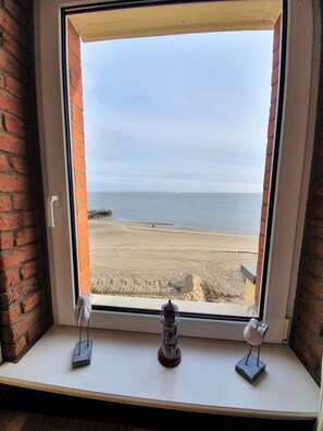 Ein Fenster mit Blick auf einen Strand, eine Lampe und eine Vogel-Skulptur.