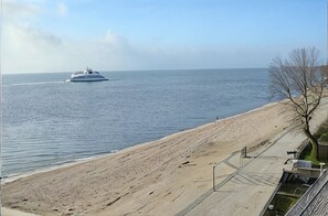 Ein Strand mit einem Boot im Wasser, einem sandigen Ufer und einem wolkenlosen Himmel.