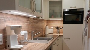 Una cocina compacta con cafetera, pileta y horno.