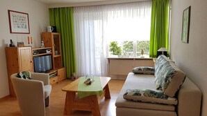 Una sala de estar con un sofá, una mesa de centro, un televisor y un mueble.