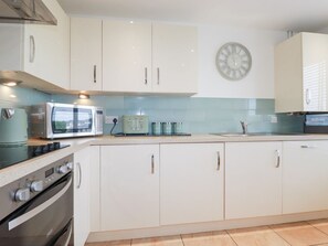 Eine Küche mit weißen Schränken, einer Mikrowelle, einem Toaster und einer Uhr an der Wand.