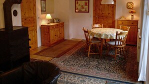 Ein gemütliches Zimmer mit einem Holztisch, Stühlen, einem Teppich, einer Lampe und einem Kamin.