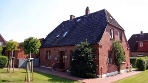 Ein rotes Backsteinhaus mit geneigtem Dach, einer Haustür und einer kleinen Veranda.