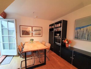 A dining area with a table, chairs, a bookshelf, a television, and artwork on the walls. - Rungholtstr. 3 a - Upper floor right - Allergy-friendly apartment with balcony & (Wyk auf Föhr)