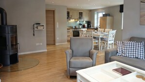Una sala de estar moderna con chimenea, un comedor y una cocina al fondo.