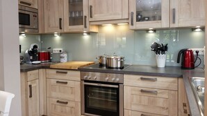 Una cocina moderna con armarios de madera, horno empotrado, microondas y cafetera.