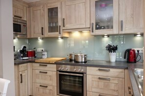 A modern kitchen with wooden cabinets, a built-in oven, a microwave, and a coffee maker. - Golfoase 2 - Semi-detached house for 6 people - Semi-detached house Golfoase 2 for 6 (Oevenum)