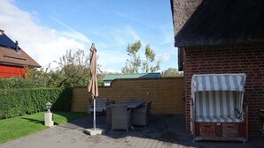 Un patio con mesa y sillas, un espacio de estar cubierto y un muro de ladrillo.