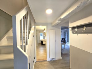 A staircase leading to a landing with a door, a hallway with a light fixture, and a chair in the background. - WattLütt - Allergy-friendly WattLütt vacation apartment with terrace & parking space (Oevenum)