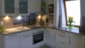 Eine moderne Küche mit weißen Schränken, einem Einbauofen, einer Spüle und einem Fenster mit Ausblick.
