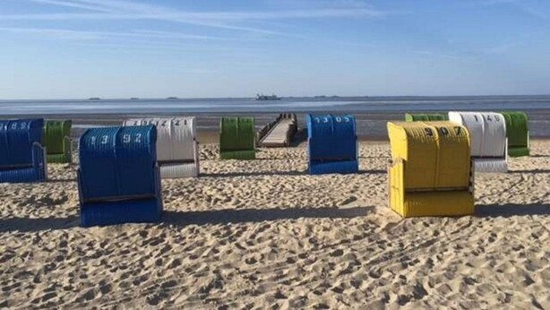 Ein Strand mit Reihen von Liegen und Sonnenschirmen.