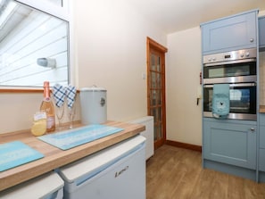 A kitchen with a refrigerator, oven, and a window with blinds. - Min Y Traeth, Bull Bay (Amlwch)