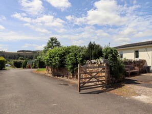A gated driveway leading to a house with a stone wall and a wooden gate. - Stable Cottage, Otterburn. TV. (Newcastle upon Tyne)
