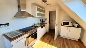 Una cocina compacta con estufa, horno, microondas y una lámpara colgante.