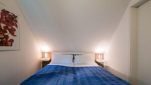 Un dormitorio con una cama, dos lámparas de noche y un cuadro en la pared.