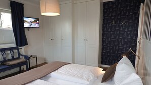 Ett sovrum med två sängar, en TV, en bänk och en garderob.