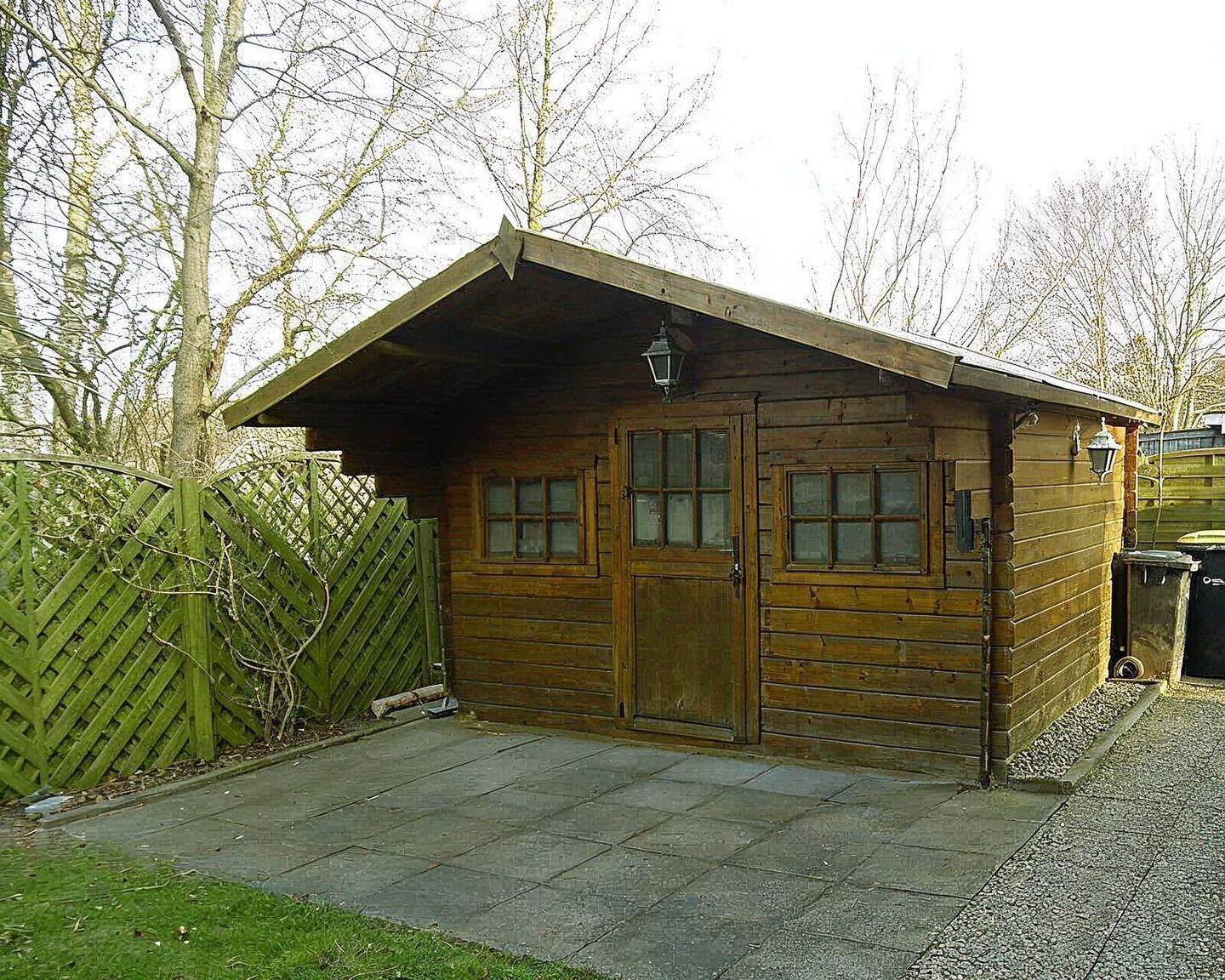Eine Holzhütte mit geneigtem Dach, zwei Türen und einer kleinen Veranda.