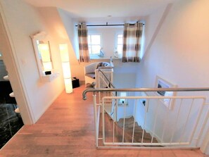 A staircase with a metal railing, a wicker chair, and a window with curtains. - Grote Fischerhuus - Holiday home Grote Fischerhuus: 110 m², close to the beach, (Wyk auf Föhr)
