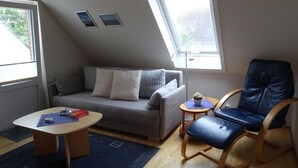 Ett litet, ombonat rum med en soffa, en fåtölj, ett litet bord och ett fönster.