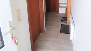 Ein Korridor mit Holztüren, einer Leuchte, einem Gemälde und einem gerahmten Bild an der Wand.