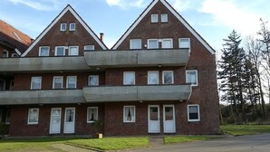 Ein zweistöckiges Wohngebäude mit einer symmetrischen Fassade, zahlreichen Fenstern und einem zentralen Eingang.