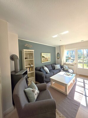 A living room with a sofa, a coffee table, a bookshelf, and a fireplace. - Eulenkamp 8 c - DHH right - Holiday home in Wyk auf Föhr: 200 m to the beach, (Wyk auf Föhr)