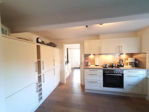Eine moderne Küche mit weißen Schränken, einem eingebauten Backofen und einer Kaffeemaschine.