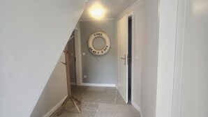 A hallway with a stone floor, a black mat at the entrance, and a life ring on the wall. - Uijs Hüs - Allergy-friendly vacation home Uijs Hüs with garden & terrace in (Borgsum)