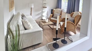 A modern living room with a sofa, chairs, a coffee table, and a lamp. - Uijs Hüs - Allergy-friendly vacation home Uijs Hüs with garden & terrace in (Borgsum)