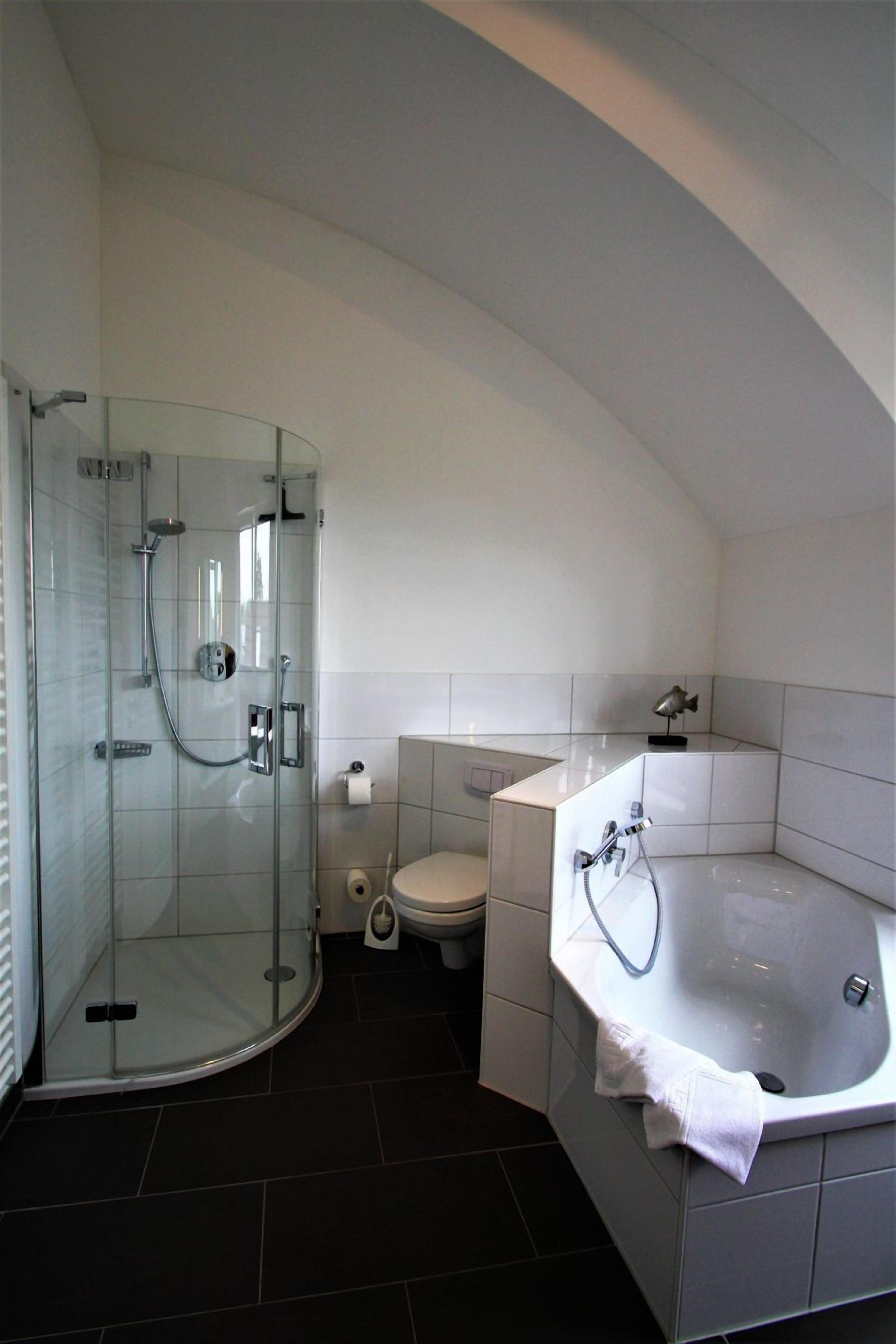 Ein modernes Badezimmer mit einer begehbaren Glasdusche, einer Toilette und einer großzügigen Badewanne.