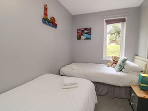 A bedroom with two beds, a window with a view of greenery, and a teddy bear on one bed. - Valley Lodge 55, Gunnislake (Callington)