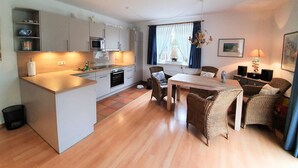 Un espacio habitable compacto con kitchenette, comedor y zona de estar.
