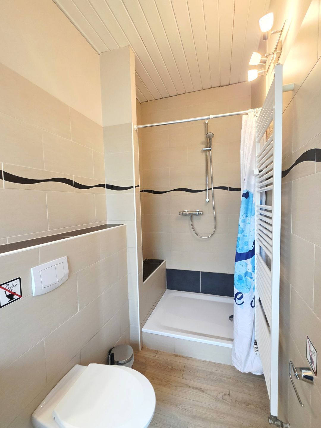 A compact bathroom with a shower, toilet, and a towel rack.