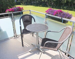 A balcony with a round table and two chairs, surrounded by a glass railing. - Kiebitz - Allergy-friendly vacation apartment Kiebitz with balcony near the beach in (Wyk auf Föhr)