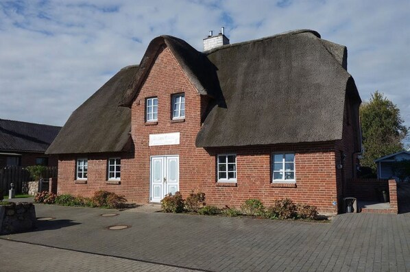 A brick building with a thatched roof, a sign indicating it is a pub, and a paved entrance area. - Golfoase 1 - Semi-detached house for 6 people - Golfoase 1: Semi-detached house for 6 people (Oevenum)