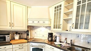 A kitchen with white cabinets, a wooden countertop, a built-in oven, and a sink. - Golfoase 1 - Semi-detached house for 6 people - Golfoase 1: Semi-detached house for 6 people (Oevenum)