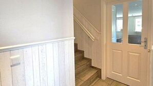 A staircase with wooden steps and white walls, leading to a door with a glass panel. - Golfoase 1 - Semi-detached house for 6 people - Golfoase 1: Semi-detached house for 6 people (Oevenum)