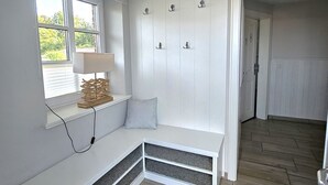 A room with a built-in bench, a window with blinds, a wall-mounted coat rack, and a door leading to another room. - Golfoase 1 - Semi-detached house for 6 people - Golfoase 1: Semi-detached house for 6 people (Oevenum)