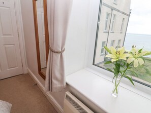 A room with a window, a white radiator, and a vase with flowers on the windowsill. - Seaview Retreat in Coverack (Coverack)