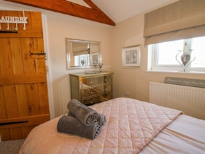 A bedroom with a bed, a dresser, a mirror, a window with a view, and a door labeled 'laundry'. - Hillview Stottesdon Shropshire (Kidderminster)