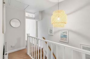 Una escalera con barandillas blancas y un candelabro colgante.