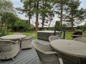 Eine Terrasse mit Korbmöbeln und einem Whirlpool.